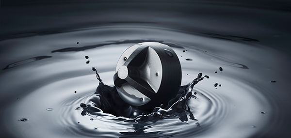 A black spherical object splashing into dark water, creating concentric circular ripples and spreading droplets.